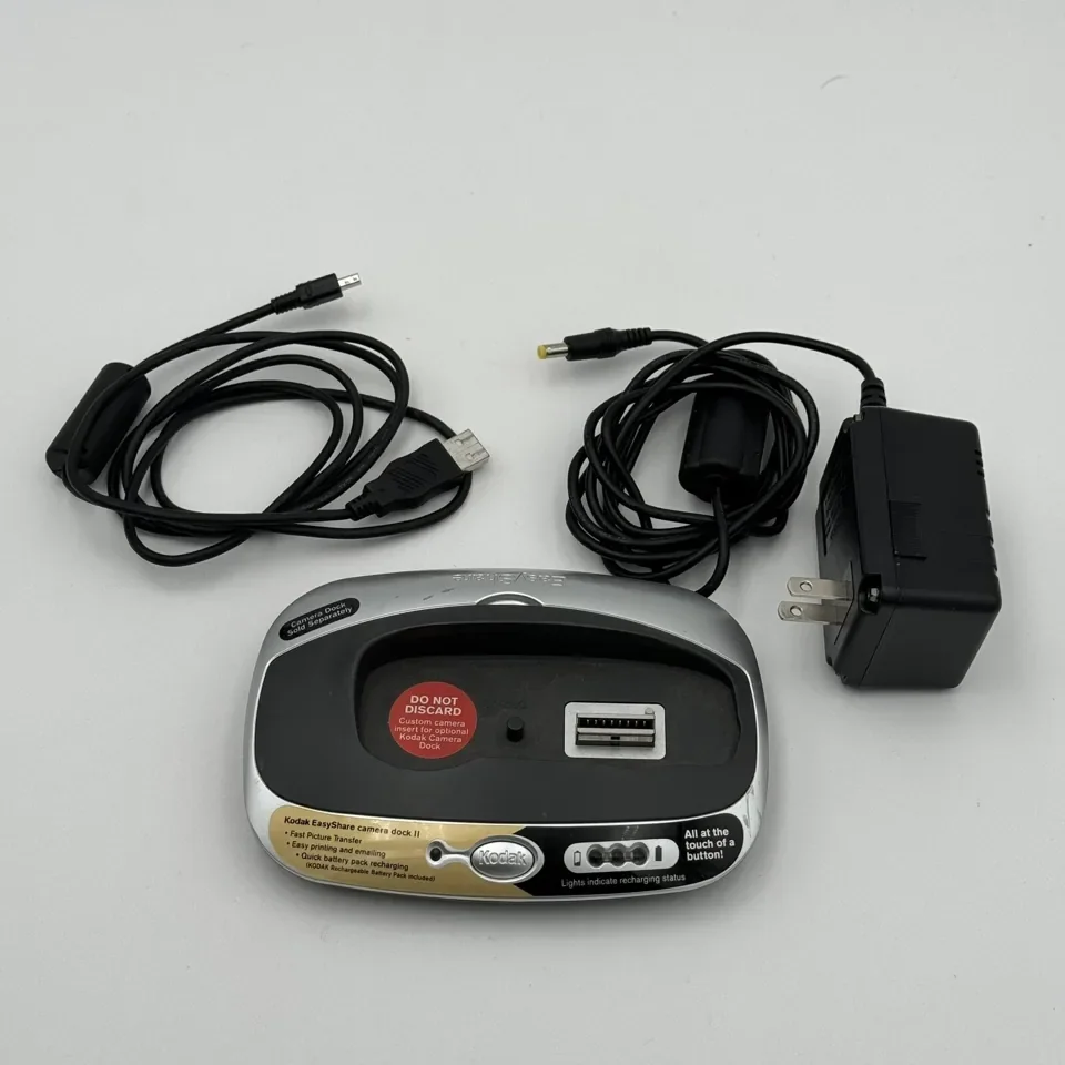 A Kodak EasyShare camera dock with its USB cable and power adapter laid out beside it