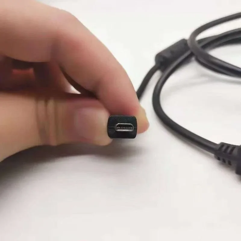 A hand holding the small camera-end plug of a black Panasonic camera cable