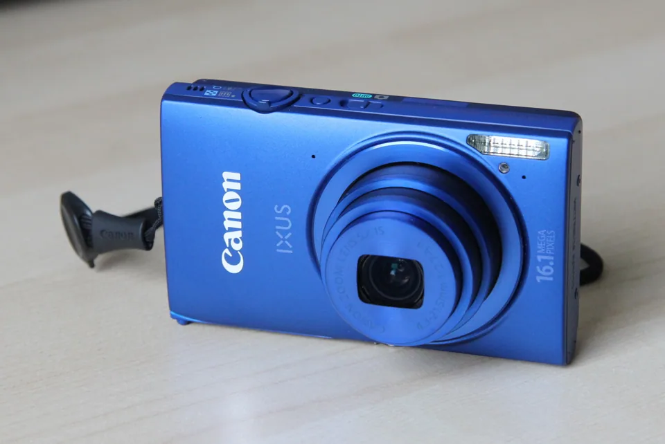 The Canon IXUS 240 HS (ELPH 320 HS in the US), a blue example, seen from the front.