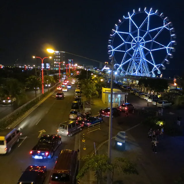 A city street at night with a Ferris wheel