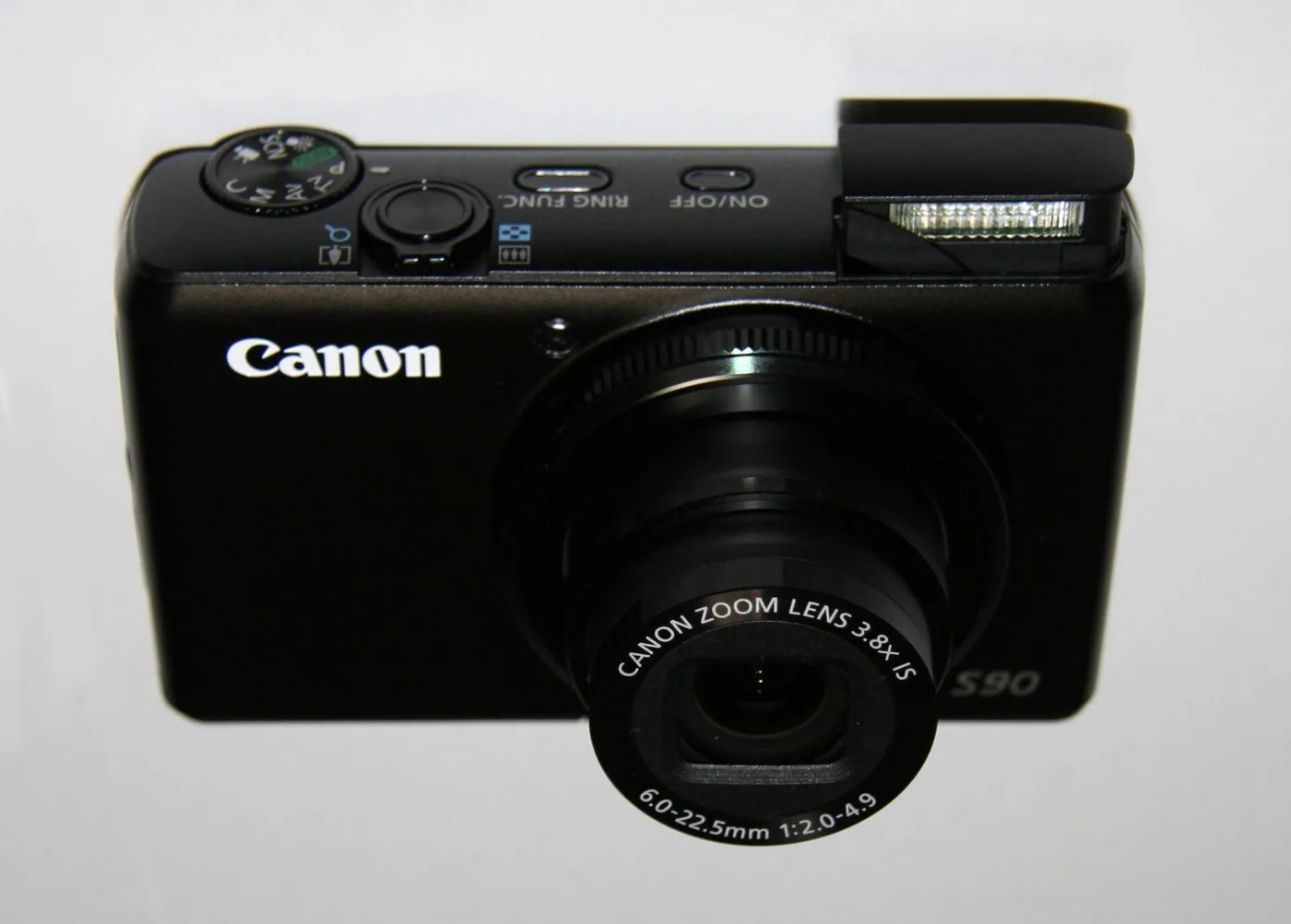 The Canon PowerShot S90 with its motorised flash raised above the lens.