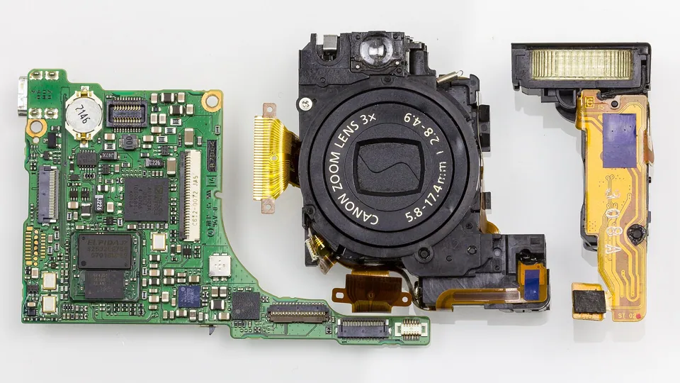 Everything on one table: the circuit board, the zoom lens and the flash of a taken-apart IXUS 70. For a camera that fit in a pocket, there was a lot in there.