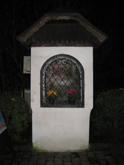 A small roadside shrine at night, lit by flash