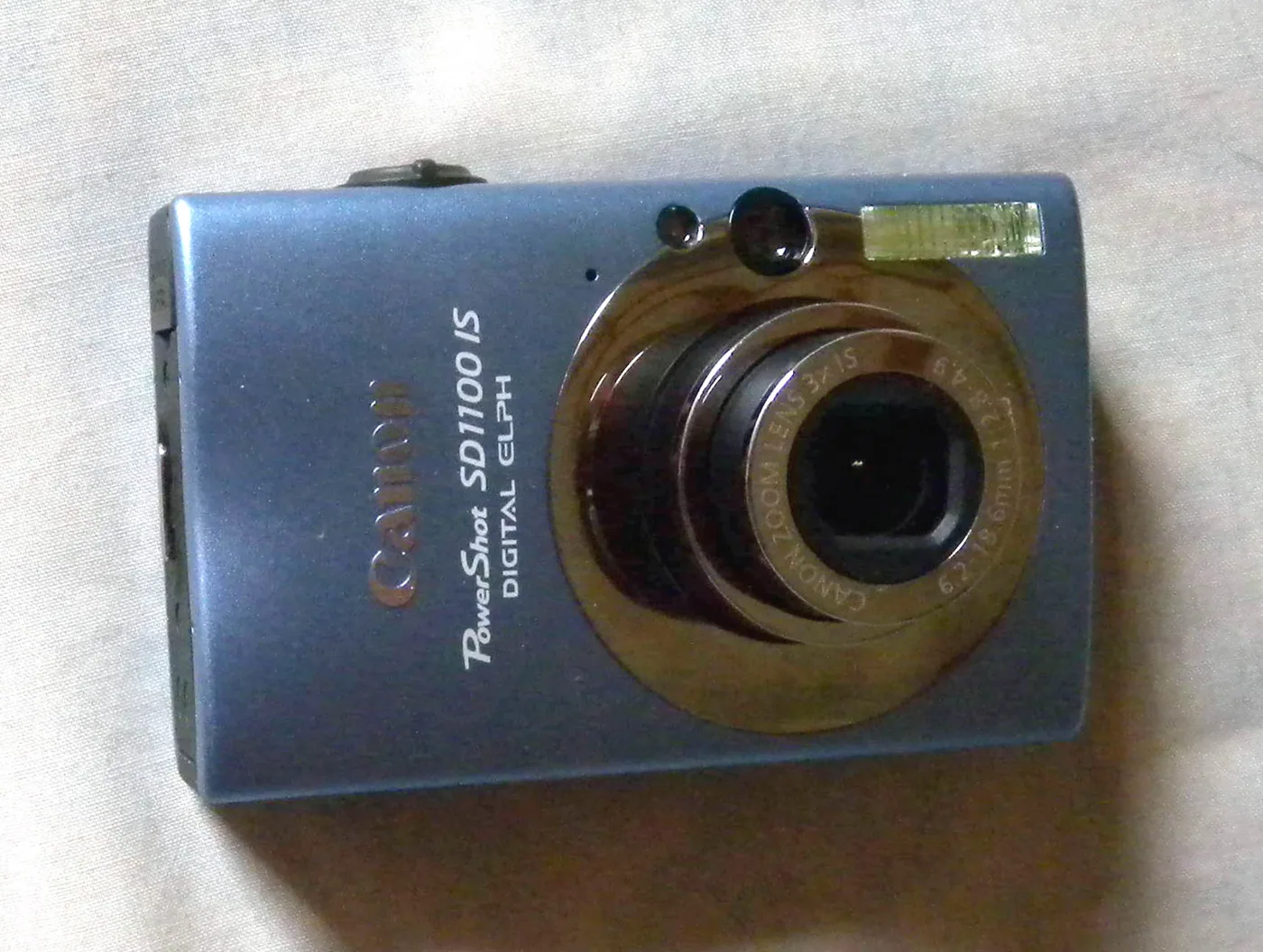 The Canon PowerShot SD1100 IS in blue, with its lens-shift stabilised 3x zoom.