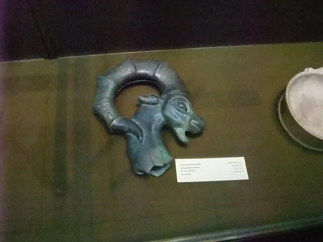 A metal ram-head vessel in a museum case
