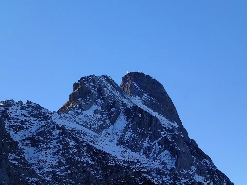 A snow-capped mountain under a blue sky, photographed with an Olympus Tough TG-1. We found no free-licence photo of the camera itself.