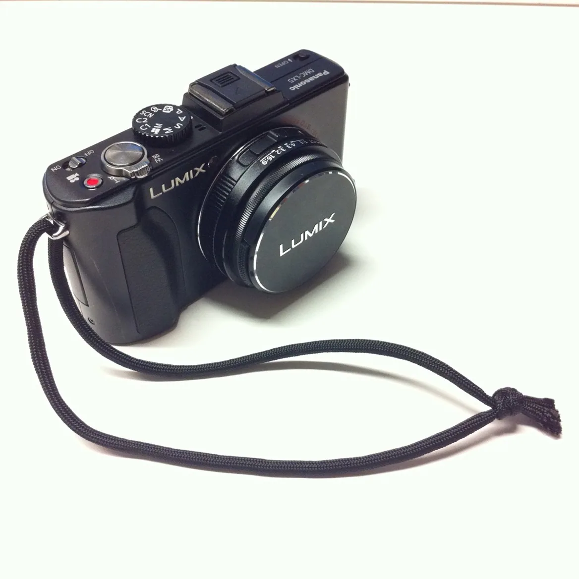 The Panasonic Lumix DMC-LX5 with its lens cap on a strap.