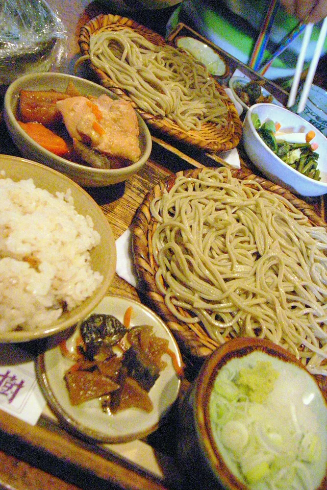 A bowl of soba noodles at lunch, handheld in a restaurant.