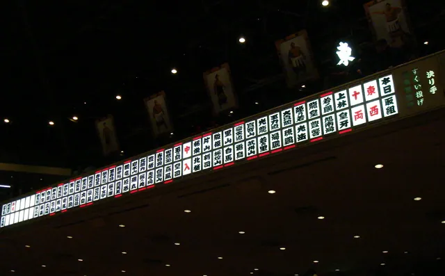 An electric scoreboard in a dim sumo hall
