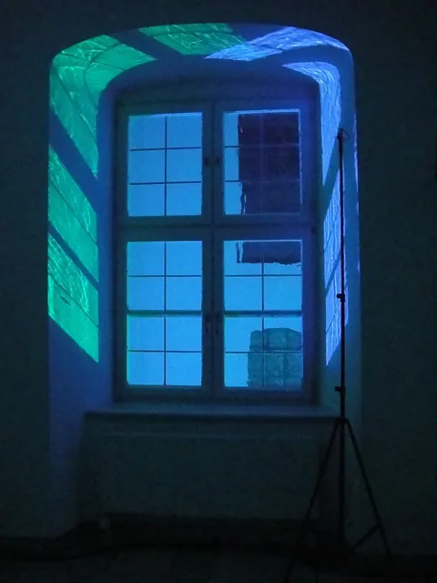 A window lit blue in a dark room