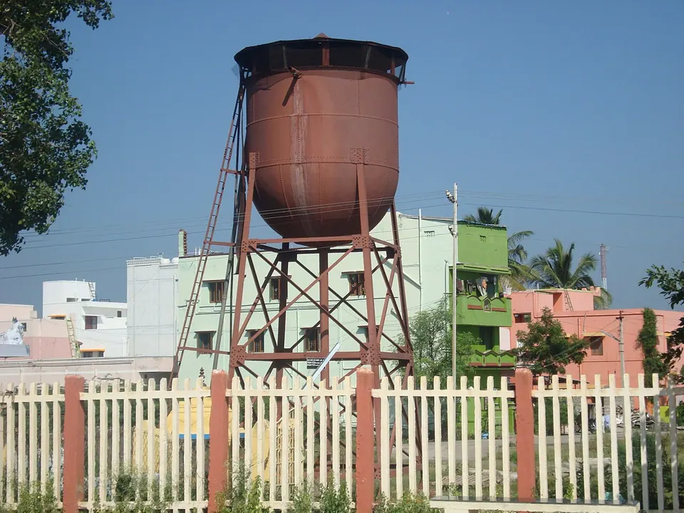 A rusting water tower beside a street, photographed with a Sony DSC-W120.